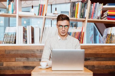 Dizüstü bilgisayar kullanırken kafede oturan çekici adam