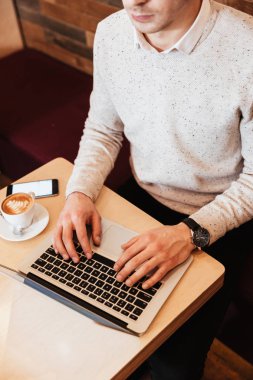 Kafede dizüstü bilgisayar kullanan biri kırpılmış görüntü.