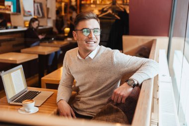 Bir kenara arayan kahvede oturan neşeli adam