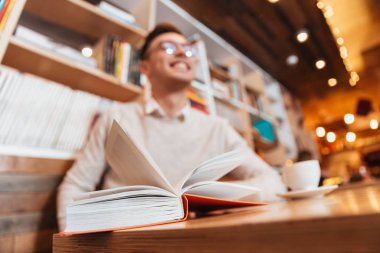 Kafede oturan gözlüklü genç neşeli adam