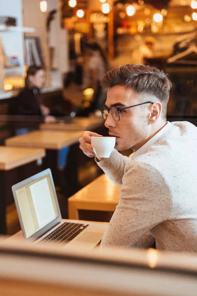 Atrakcyjne młody człowiek siedzi w kawiarni, podczas picia kawy. — Zdjęcie stockowe