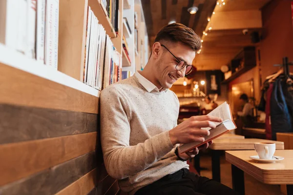 Homem feliz sentado no café enquanto lê o livro — Fotografia de Stock