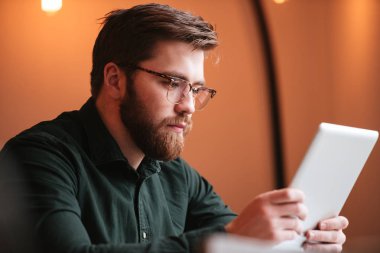 Tablet bilgisayar kullanarak sakallı yakışıklı genç.