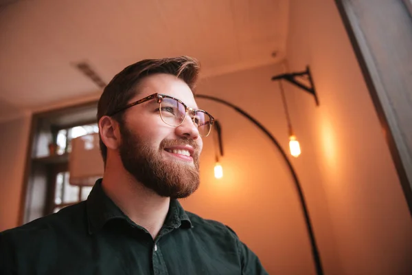 Guapo barbudo joven sentado en la cafetería . — Foto de Stock