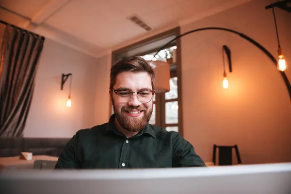 Sourire jeune homme barbu à l'aide d'un ordinateur portable . — Photo