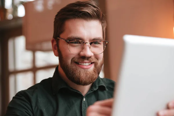 Cheerful bearded young man using tablet computer. — Stock Photo, Image