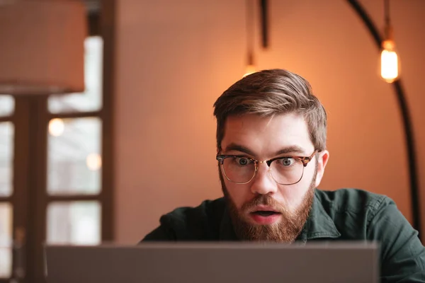 Jovem barbudo confuso usando computador portátil . — Fotografia de Stock