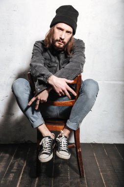 Sandalyede oturan ve elleriyle işaret şapkalı adam