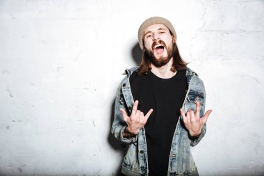 Sakallı çığlık hipster adam rock jest yapmak.
