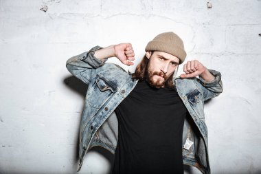 Duvar arka plan üzerinde poz çekici sakallı hippi adam.