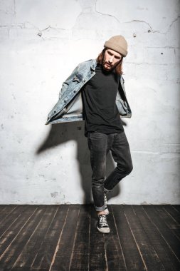 Yakışıklı sakallı hippi adam duvar arka plan üzerinde poz.