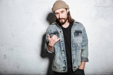 Çekici sakallı hippi adam elleriyle işaret.