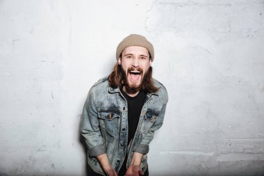 Duvar arka plan üzerinde poz sakallı hippi adam çığlık.