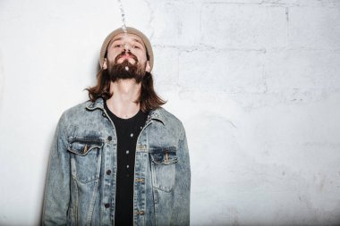 Duvar arka plan üzerinde poz hipster adam genç sakallı.