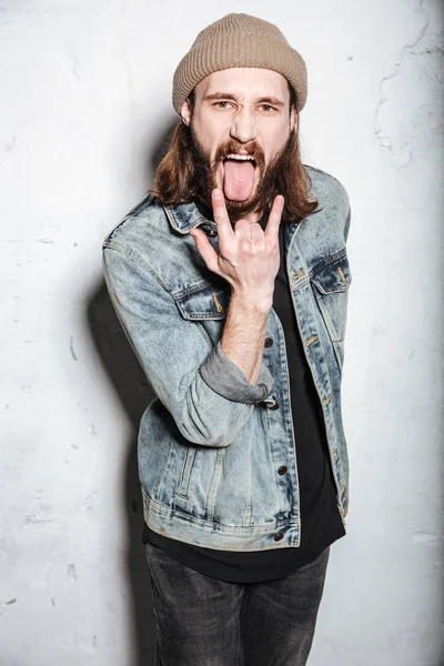 Gritando barbudo hipster hombre hacer rock gesto y mostrando lengua . —  Fotos de Stock