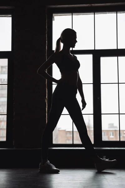 Σιλουέτα της γυναίκας αθλητής που στέκεται κοντά στο παράθυρο — Φωτογραφία Αρχείου