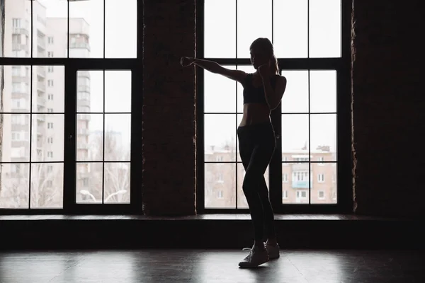 Σιλουέτα του αθλητή γυναίκα στέκεται και κάνει ασκήσεις σκιώδους πυγμαχίας — Φωτογραφία Αρχείου