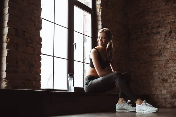 Schöne junge Fitness-Dame sitzt im Fitnessstudio — Stockfoto