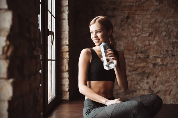 Glückliche Fitness-Frau trinkt Wasser und schaut zur Seite. — Stockfoto