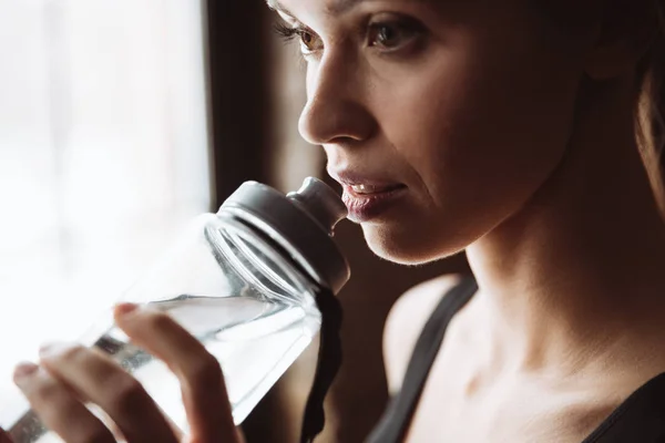 Hübsche junge Fitness-Frau trinkt Wasser. — Stockfoto