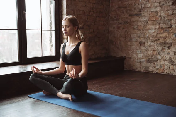 Idrottskvinna gör yoga och meditera i studio — Stockfoto