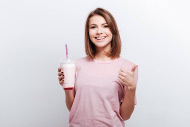 Güzel genç bayan kokteyl holding ve başparmak yukarıya jest yapmak