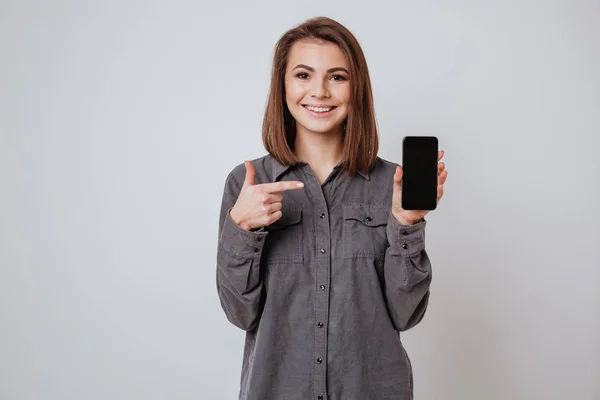 Jovencita sonriente mostrando la pantalla del teléfono móvil a la cámara . — Foto de Stock