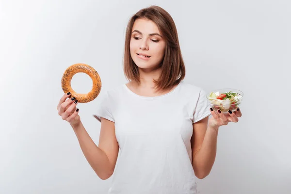 Hongerige jonge dame holding bagel en salade — Stockfoto