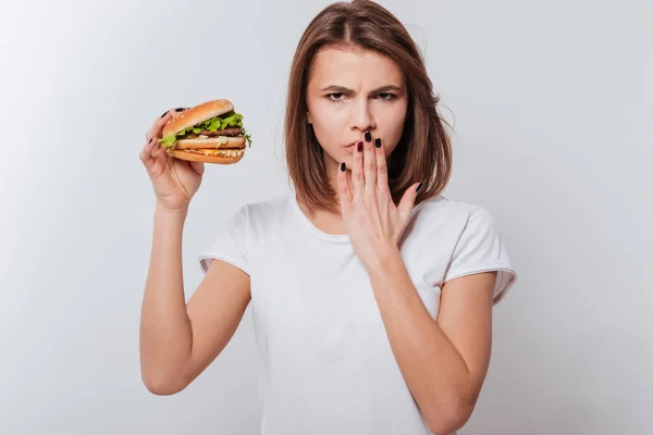Angry woman holding fastfood and covering mouth — Stock Photo, Image