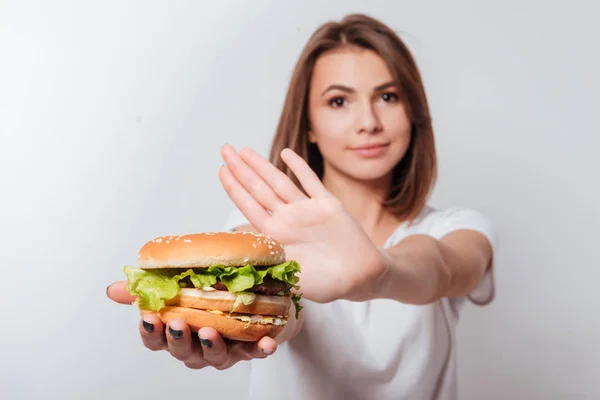 Serieuze jonge vrouw weergegeven: Fast-Food naar camera — Stockfoto