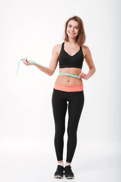 Glimlachend jonge fitness vrouw maatregel haar taille met centimeter — Stockfoto