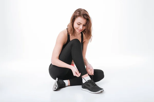 Pretty young fitness lady sitting and tie laces — Stock Photo, Image