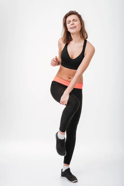 Triste jovem fitness senhora com doloroso segurando pernas — Fotografia de Stock