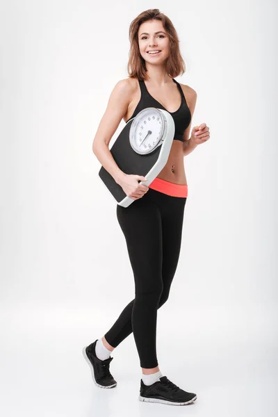 Feliz joven fitness dama sosteniendo escamas — Foto de Stock