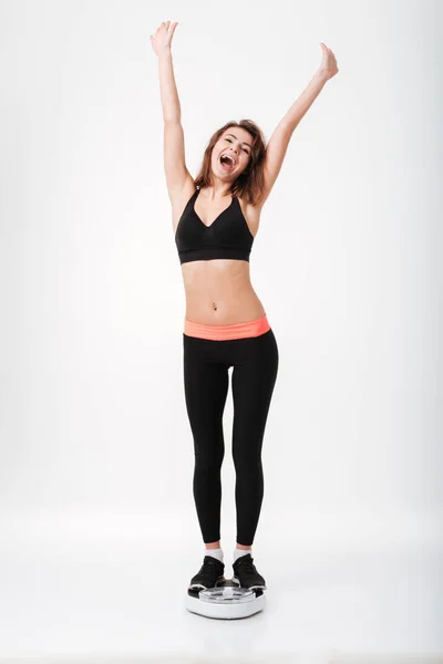 Mujer fitness feliz de pie con las manos levantadas en la escala de ponderación —  Fotos de Stock