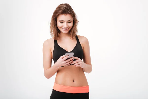 Glada attraktiv ung idrottskvinna med mobiltelefon — Stockfoto