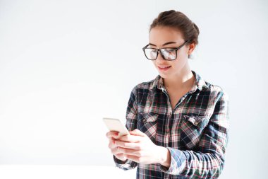 Ayakta ve cep telefonuyla gözlük gülümseyen genç kadın