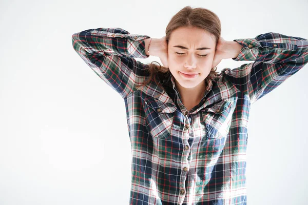 Fruncir el ceño mujer estresada en camisa a cuadros cubierto de orejas por las manos — Foto de Stock