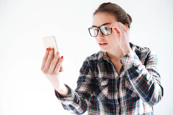 Mujer bastante joven en gafas sosteniendo y utilizando el teléfono móvil — Foto de Stock