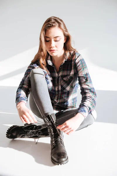 Mladá dáma sedí na podlaze na studio a kravata laces — Stock fotografie