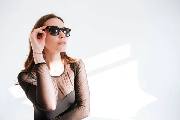 Young lady wearing sunglasses standing at studio — Stock Photo, Image