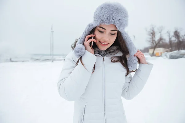 Mujer joven concentrada usando sombrero hablando por su teléfono . — Foto de Stock