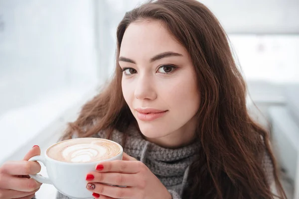 かなり若い女性がコーヒーを飲みながらセーターに身を包んだ. — ストック写真