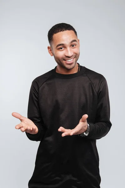 Feliz joven afroamericano guapo sosteniendo copyspace en las palmas —  Fotos de Stock