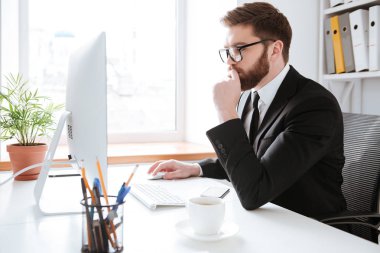 Konsantre genç sakallı işadamı bilgisayar kullanarak