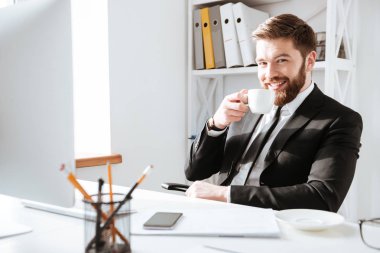 Kahve içme ve bilgisayar kullanarak neşeli işadamı