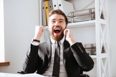 Mutlu işadamı tarafından telefon ve yapmak kazanan jest konuşmak.
