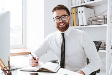 Neşeli işadamı notları yazarken ofisinde oturuyor