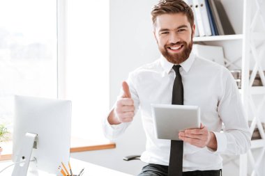 Tutan işadamı tablet ve başparmak yukarıya jest yapmak.