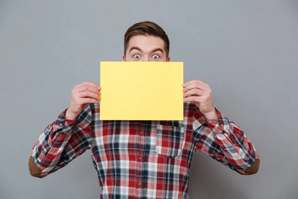 Cheerful shocked young bearded man holding copyspace blank — Stock Photo, Image
